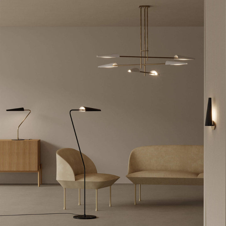 Modern interior with a chandelier, floor lamp, and sofa against a plain wall.