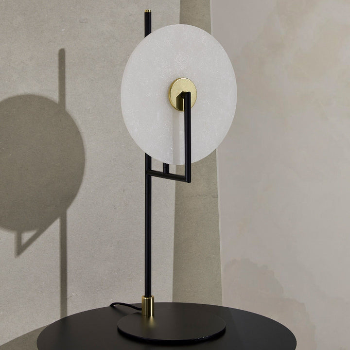 Modern table lamp with white circular shade and black base on a neutral background