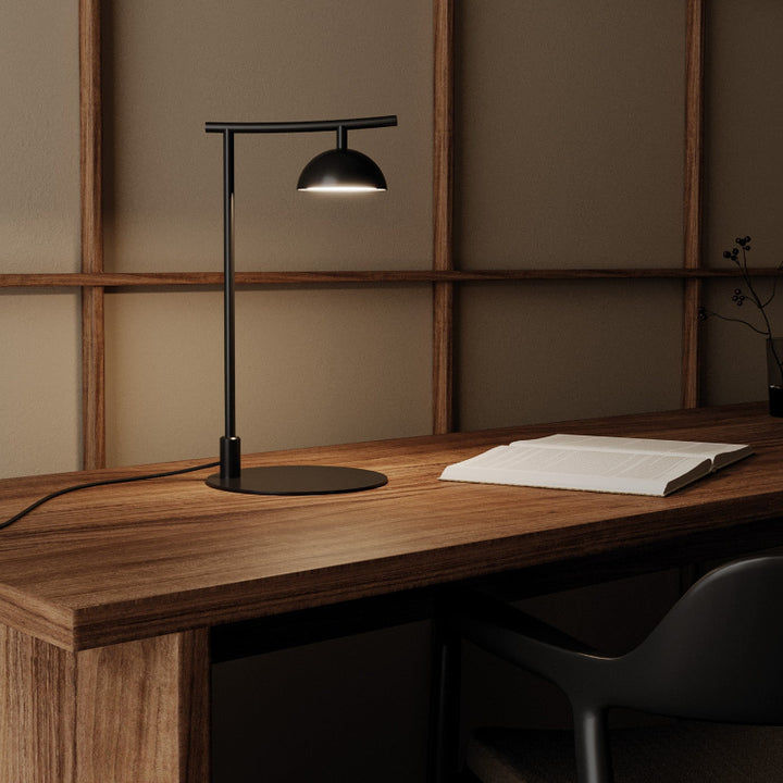 Modern Tanan black desk lamp on a wooden desk with a minimalistic background by Bazar Mondiale and Aromas Del Campo