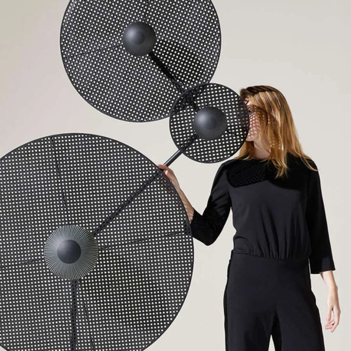 Woman holding a large black and white abstract sculpture against a plain background