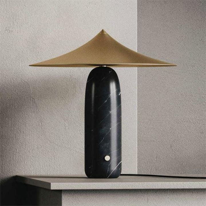 Table lamp with a black base and gold shade on a neutral background. Interior Design inspiration by Bazar Mondiale