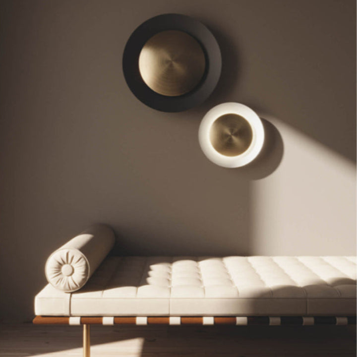Modern white bench with a cushion against a brown wall with decorative circular wall art.