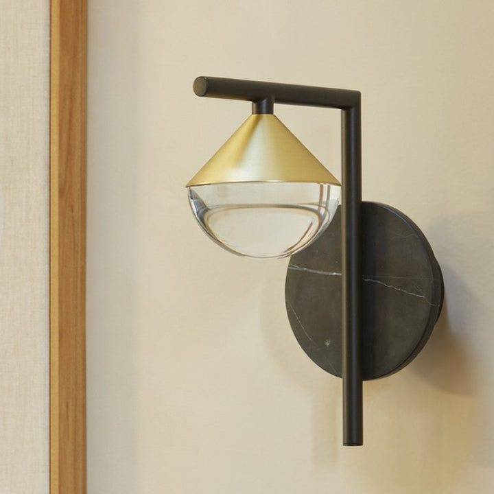 Wall-mounted light fixture with gold and black design on a neutral wall.