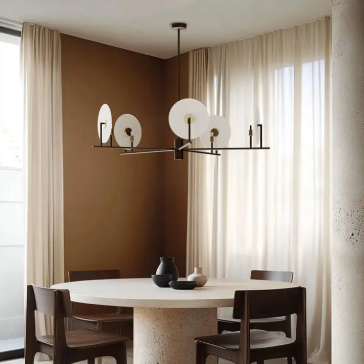 Modern dining room with a round table, chairs, and a stylish chandelier by Bazar Mondiale