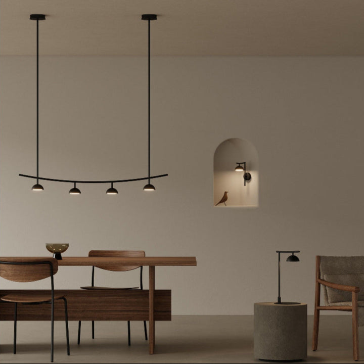 Modern dining area with a chandelier, table, chairs, and wall-mounted light fixture.