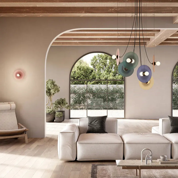 Modern living room with a sectional sofa, colorful pendant lights, and large windows.