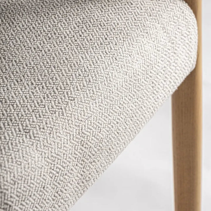 Fabric detail showing textured beige weave and ash wood leg junction – Only at Bazar Mondiale high end furniture and exclusive pieces.